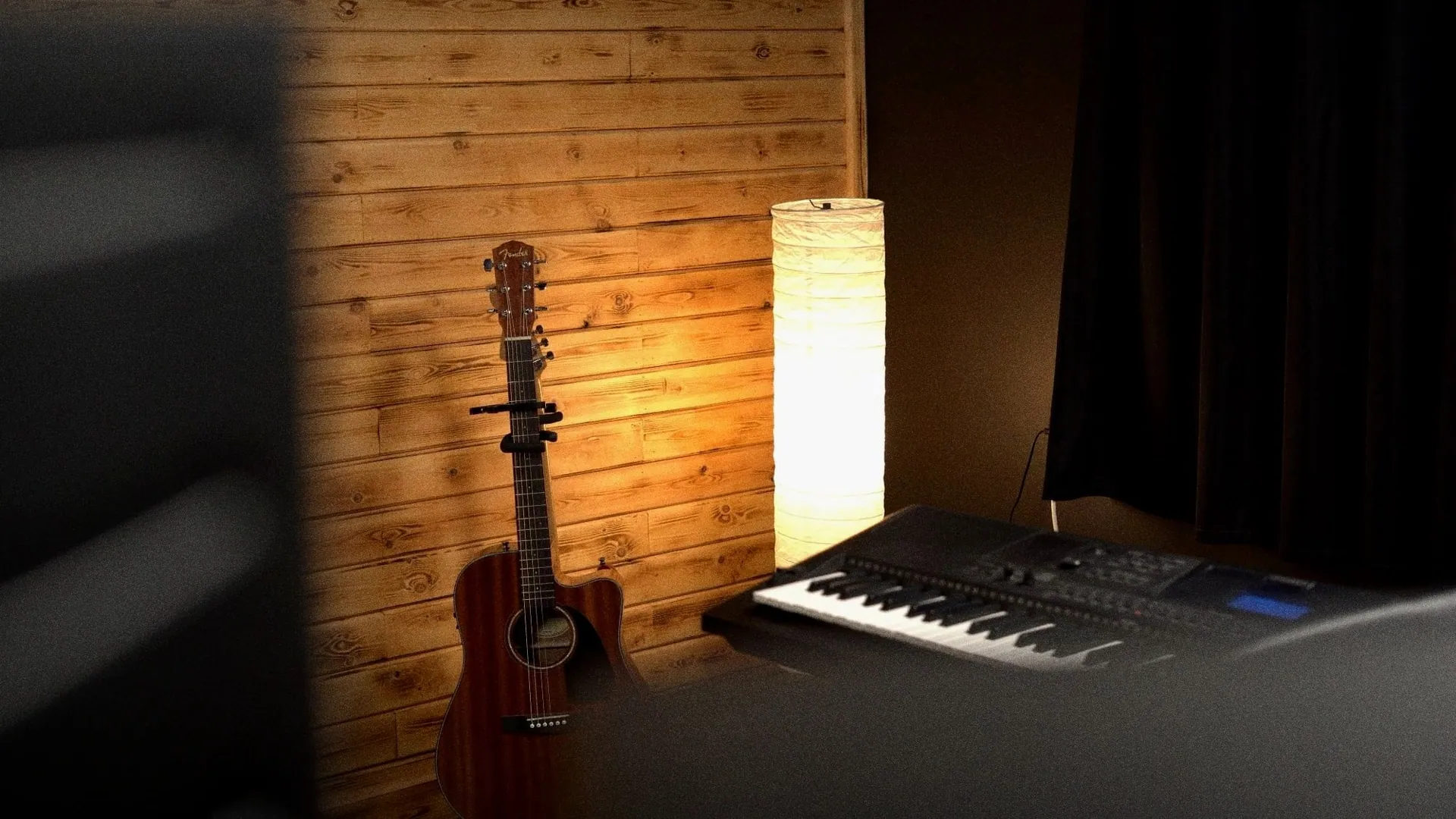 An acoustic guitar beside a lamp and a keyboard in the Rush Production House studio