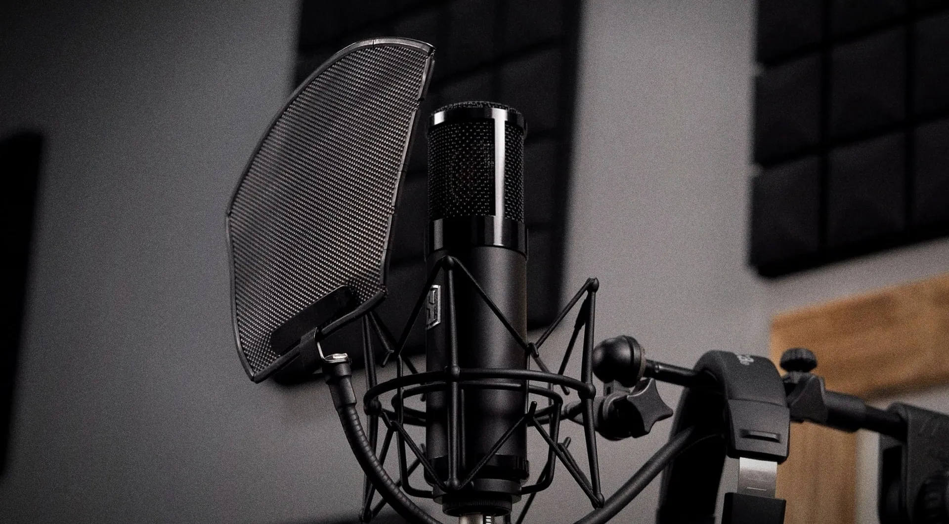 A condenser microphone with a pop filter and headphones in the Rush Production House recording booth